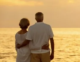 Senior couple seen from behind watching a sunset over the ocean