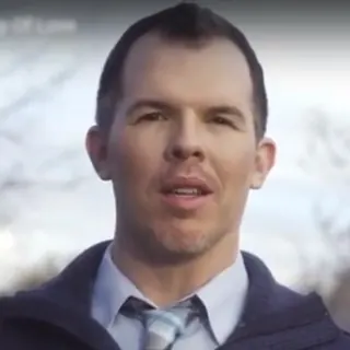Smiling man in a sweater and tie reviewing life insurance options
