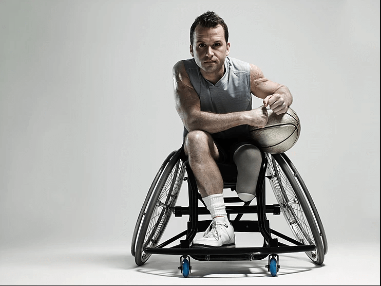 Man in a wheelchair holding a basketball on an outdoor court