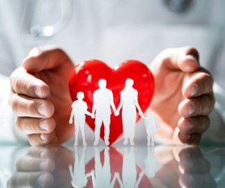 Hands cupping a paper cutout of a family beside a red heart