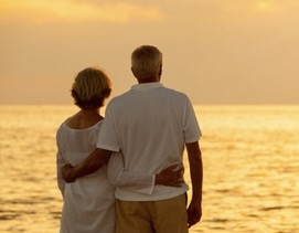 Senior couple seen from behind watching a sunset over the ocean